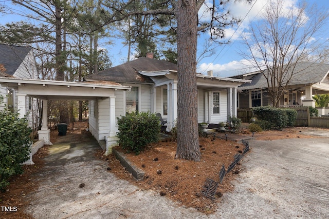 ranch-style house with driveway, a chimney, fence, and a carport