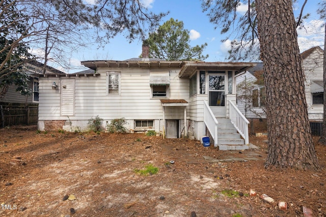 rear view of property featuring a chimney and fence