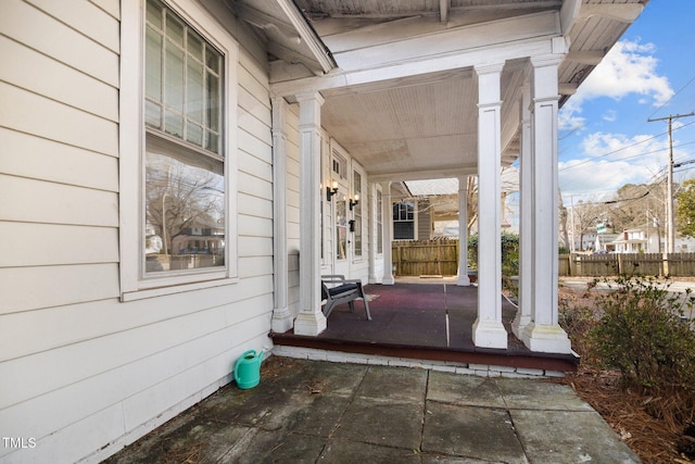 view of patio featuring a porch and fence