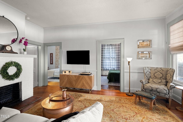 living area with ornamental molding, a textured ceiling, and wood finished floors