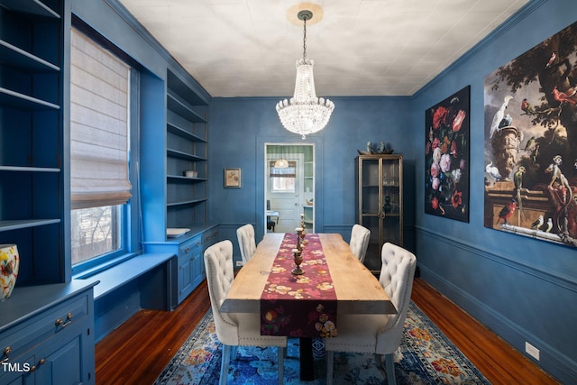 dining room featuring ornamental molding, dark wood-type flooring, built in features, and a notable chandelier