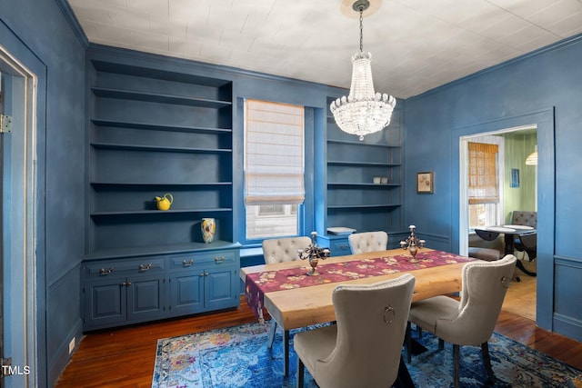 dining space featuring ornamental molding, dark wood-type flooring, an inviting chandelier, and built in features