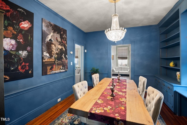 dining room featuring an inviting chandelier, crown molding, built in shelves, and dark wood-style flooring