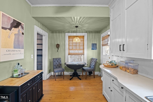 interior space featuring ornamental molding, light wood-type flooring, and baseboards