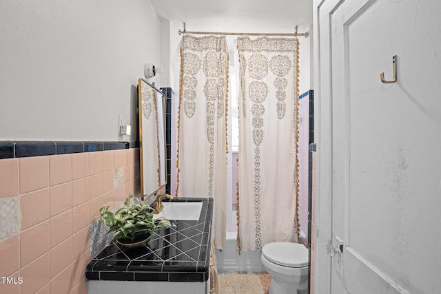 full bath with tile walls, shower / bath combination with curtain, toilet, wainscoting, and vanity