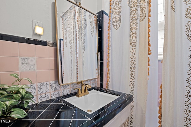 bathroom featuring a sink and tile walls