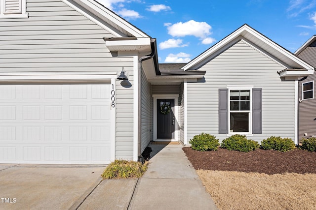 view of exterior entry featuring a garage and driveway