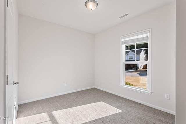 carpeted empty room with plenty of natural light, visible vents, and baseboards