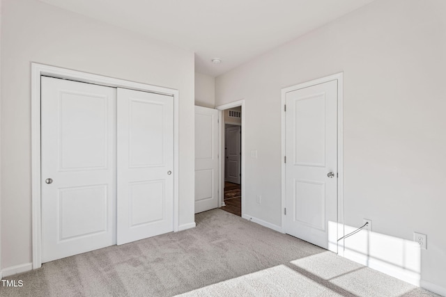 unfurnished bedroom with carpet, a closet, and baseboards