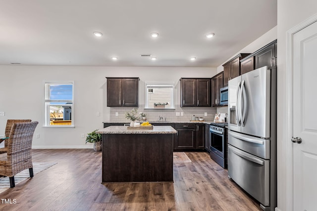 kitchen with stainless steel appliances, a kitchen island, dark brown cabinets, and tasteful backsplash