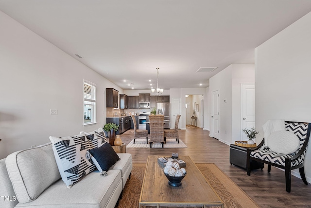 living room with a chandelier, recessed lighting, visible vents, and wood finished floors