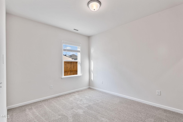 spare room featuring carpet floors, visible vents, and baseboards