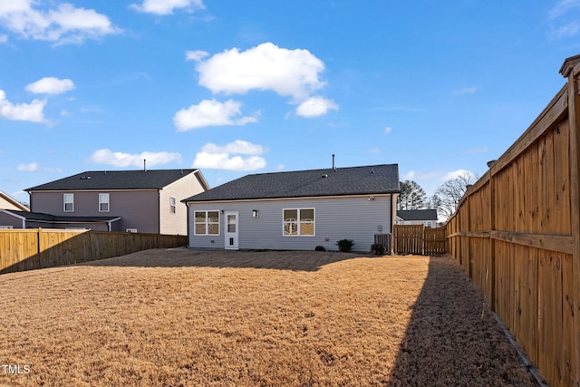 rear view of property with central air condition unit, a fenced backyard, and a lawn