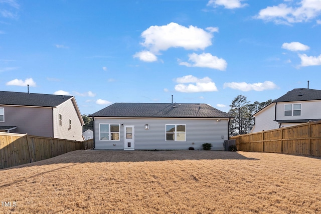 rear view of property featuring a fenced backyard, central AC unit, and a lawn