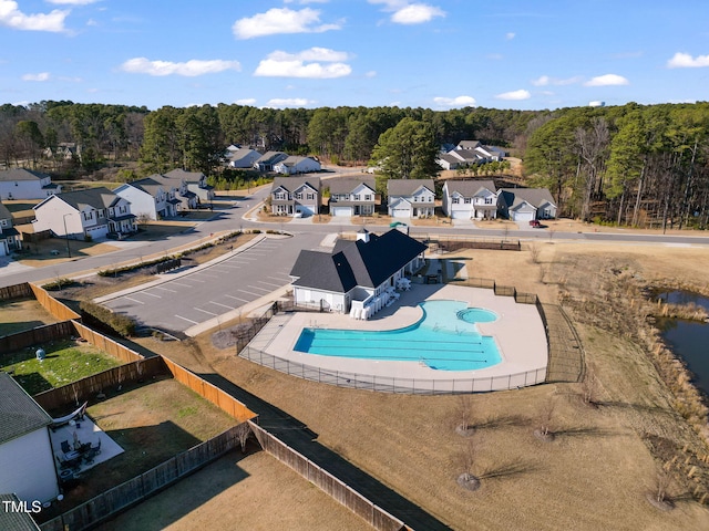 community pool featuring a patio area, a fenced backyard, a residential view, and a wooded view