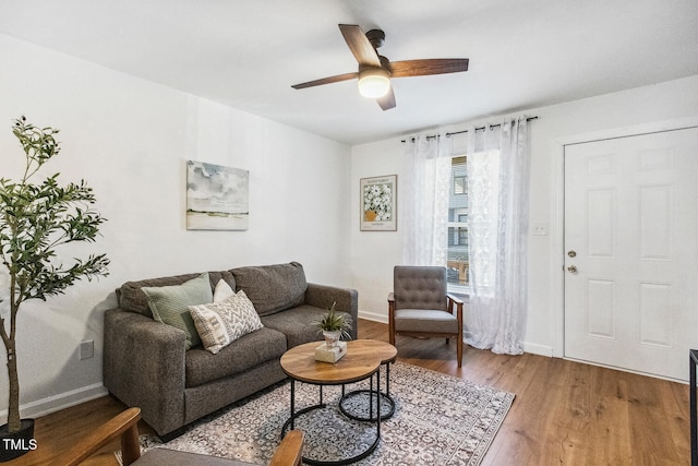 living area featuring baseboards, a ceiling fan, and wood finished floors