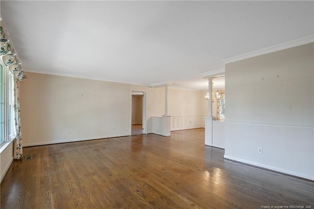 empty room featuring a chandelier, ornamental molding, wood finished floors, and visible vents