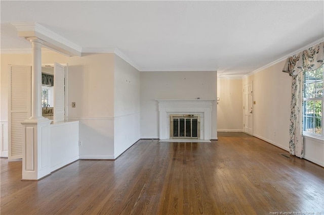 unfurnished living room with decorative columns, crown molding, wood finished floors, and a fireplace with flush hearth