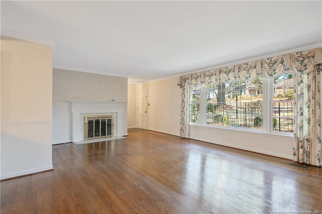 unfurnished living room with baseboards, visible vents, a fireplace with flush hearth, ornamental molding, and wood finished floors