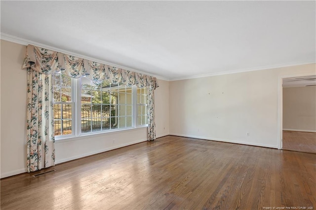 unfurnished room with visible vents, crown molding, baseboards, and wood finished floors