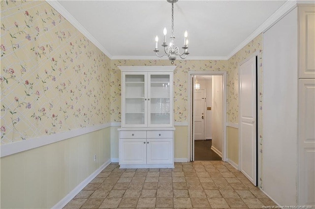 unfurnished dining area with crown molding, wainscoting, a notable chandelier, and wallpapered walls