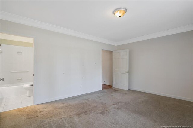 carpeted spare room featuring tile patterned flooring, crown molding, and baseboards