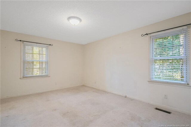 spare room featuring carpet, visible vents, and a textured ceiling