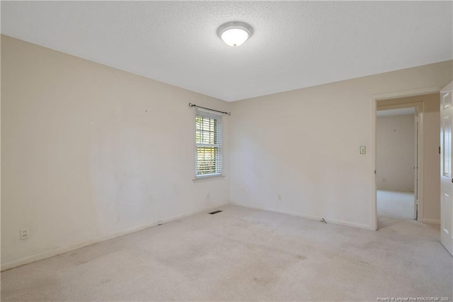 unfurnished room with a textured ceiling, carpet floors, and baseboards