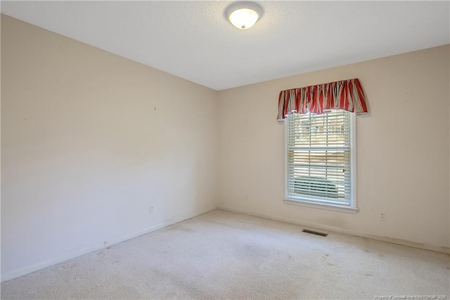 carpeted spare room featuring visible vents and a textured ceiling