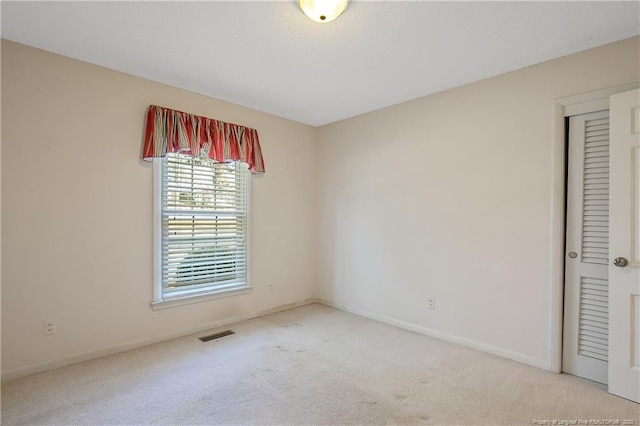 spare room with carpet flooring, visible vents, and baseboards