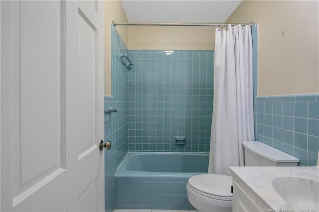 bathroom with tile walls, shower / bath combination with curtain, toilet, wainscoting, and vanity