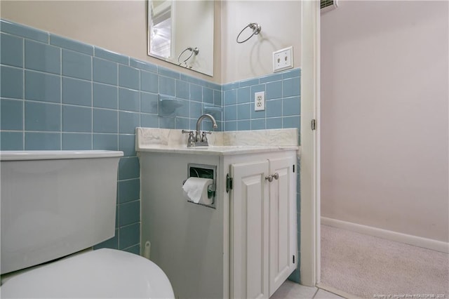 half bathroom with toilet, vanity, and tile walls