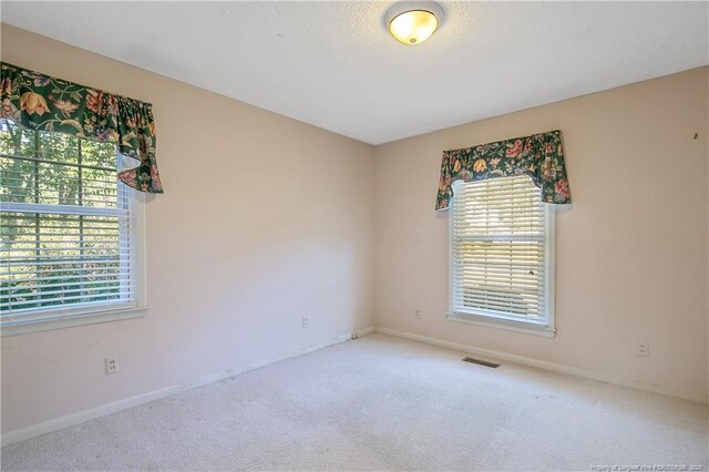 empty room featuring baseboards, carpet, visible vents, and a healthy amount of sunlight