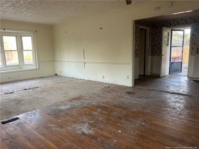 unfurnished room featuring hardwood / wood-style flooring, a textured ceiling, visible vents, and a wealth of natural light