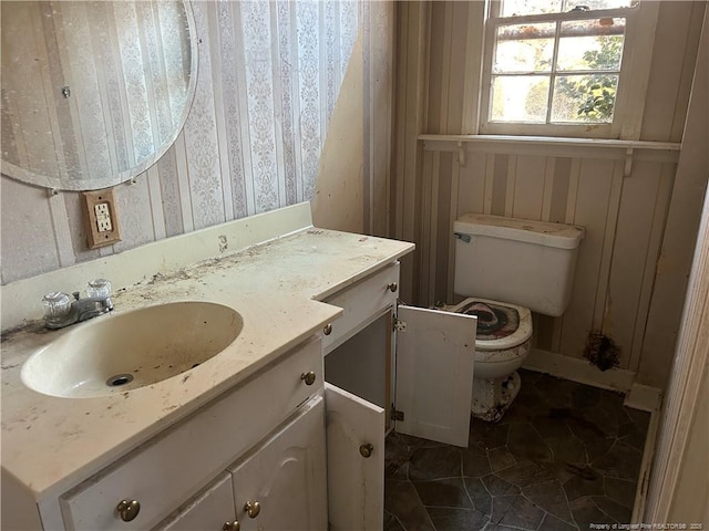 bathroom with wood walls, vanity, and toilet