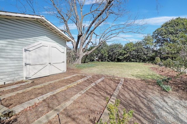 view of yard featuring a storage shed, a vegetable garden, and an outdoor structure