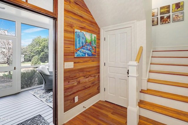 doorway to outside with stairs, wood walls, vaulted ceiling, and wood finished floors