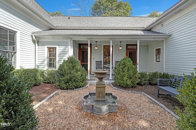 entrance to property with a shingled roof and a porch