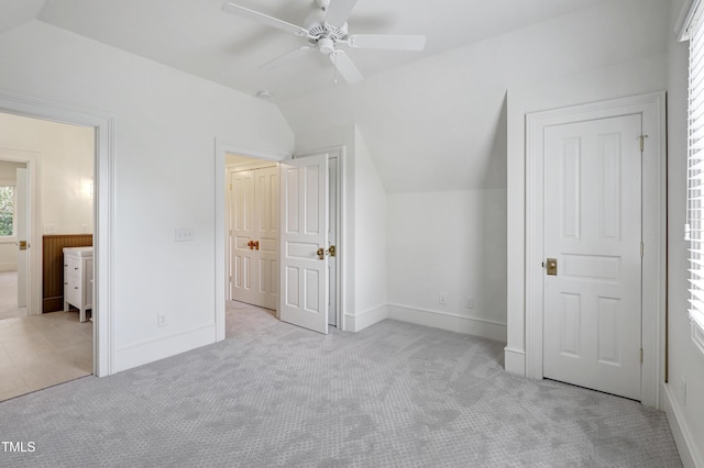 unfurnished bedroom featuring lofted ceiling, carpet floors, ensuite bath, and baseboards