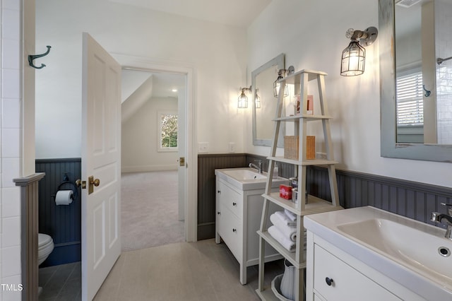 bathroom with two vanities, wainscoting, and a sink