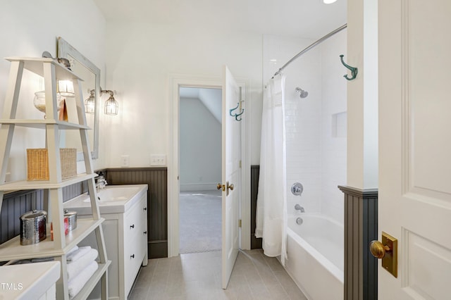 full bathroom featuring a wainscoted wall, shower / bathtub combination with curtain, and vanity