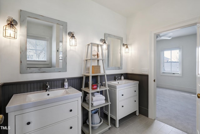 bathroom with plenty of natural light, two vanities, a sink, and wainscoting