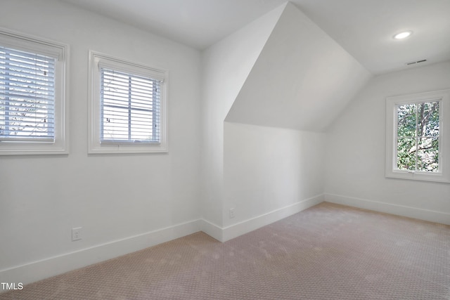 additional living space featuring light carpet, vaulted ceiling, visible vents, and baseboards