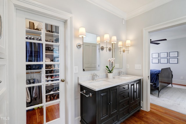 bathroom featuring double vanity, ornamental molding, a sink, and wood finished floors