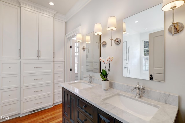 bathroom with double vanity, visible vents, a sink, and wood finished floors