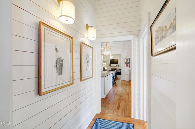 corridor with light wood-style floors and wood walls