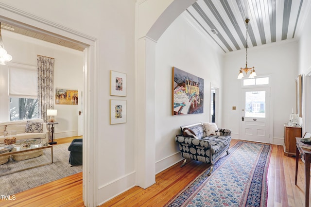 sitting room featuring an inviting chandelier, wood-type flooring, arched walkways, and baseboards