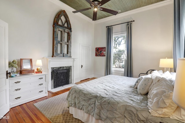 bedroom with ceiling fan, ornamental molding, hardwood / wood-style floors, and a high end fireplace