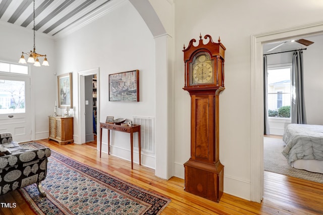 interior space featuring light wood finished floors, visible vents, arched walkways, and a notable chandelier