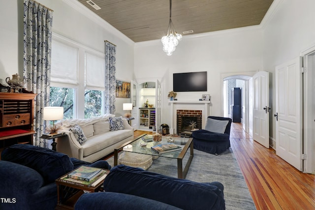 living room featuring a fireplace, crown molding, a towering ceiling, wood ceiling, and wood finished floors